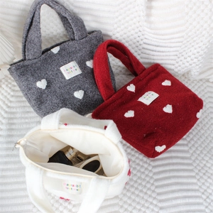 Détail de sacs fourre-tout en peluche avec broderie cœur et fermeture à glissière