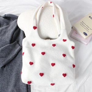 Detailed view of red heart embroidery on a white knitted tote bag with soft plush texture