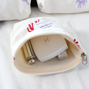 Detail of open satin cosmetic bag with red embroidery showing interior lipstick storage