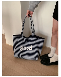 Detail of canvas tote with black and grey stripes and bold white good lettering