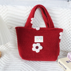 Gros plan détaillé du sac cabas en peluche rouge avec polaire douce et broderie fleurie