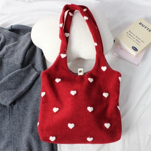 Close-up of red embroidered tote bag with white pom-pom hearts and metal snap button