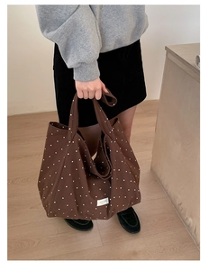 Detailed view of brown polka dot canvas tote bag featuring sturdy handles and logo patch