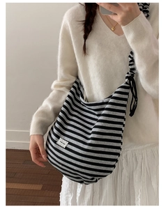 Detail of adjustable knotted shoulder strap and striped canvas texture on the hobo bag