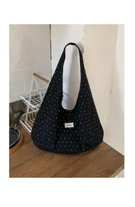 Detail of black canvas tote bag featuring white polka dots and Beyou Merci label