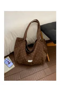 Detailed view of brown canvas tote bag with white polka dots and long shoulder straps
