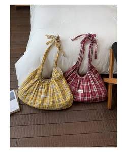 Detailed close-up of plaid tote bags featuring adjustable bow straps and fabric texture