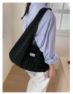Detail of black canvas shoulder bag with white star pattern and lace brand tag