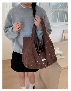 Detail of a brown polka dot canvas tote bag shown on a wooden table in a cozy home setting