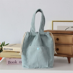 Close-up of light blue corduroy tote bag featuring a front pocket and cotton drawstring detail