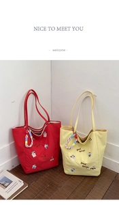 Détail de sacs fourre-tout en toile rouge et jaune avec broderies de dessins animés