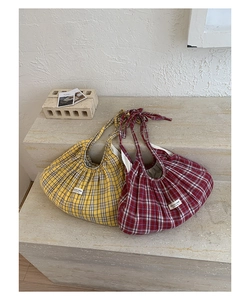 Detail of checkered tote bags in yellow and red plaid with pleated texture and logo