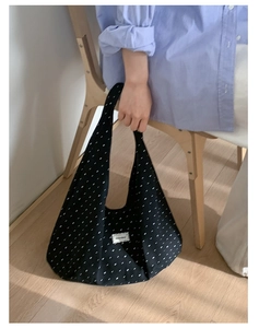 Close-up of black canvas hobo bag with white polka dots and woven label detail