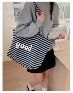 Close-up of blue and white striped canvas tote bag showing the bold printed text details