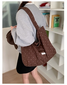 Close-up of brown polka dot canvas tote bag featuring a white decorative woven label