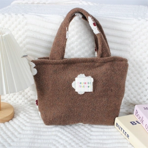 Détail du sac à main en peluche marron avec écusson nuage et texte brodé coloré