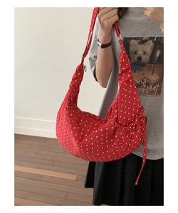 Detail of red polka dot crossbody bag featuring side drawstrings and soft canvas material
