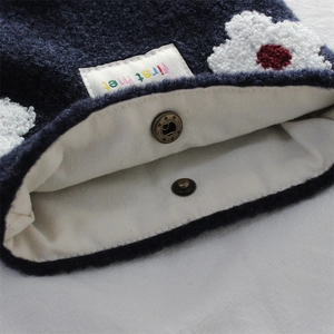 Detail of navy knit flower bag showing canvas lining and secure metal snap closure