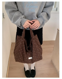 Close-up of brown polka dot canvas tote bag featuring a white square brand label