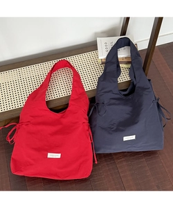 Detail of red and navy nylon tote bags with side drawstring ruching and logo patch