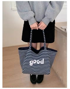 Detail view of large canvas striped tote bag with white good letter print and durable straps