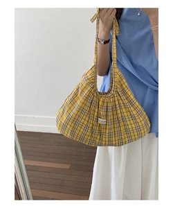 Detailed close-up of yellow plaid tote bag featuring a minimalist white woven label