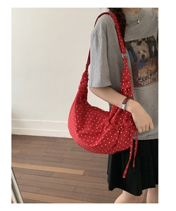 Detail of red polka dot crossbody dumpling bag with drawstring bow and zipper closure