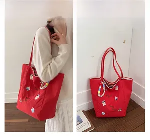 Détail du cabas en toile rouge avec broderies cartoon colorées et anses d'épaule résistantes