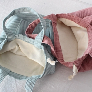 Close-up of corduroy tote bags in blue and pink with drawstring and canvas lining