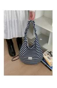 Close-up of striped shoulder bag featuring scrunched handle and lace brand label detail