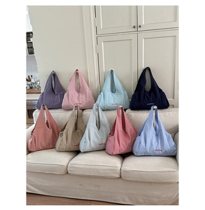 Nine stylish gingham and solid canvas tote bags displayed on a cozy white sofa