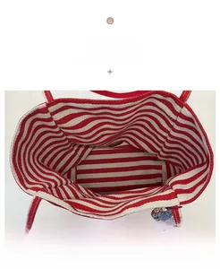 Détail de l'intérieur d'un cabas en toile avec doublure rayée rouge-blanc et breloque colorée