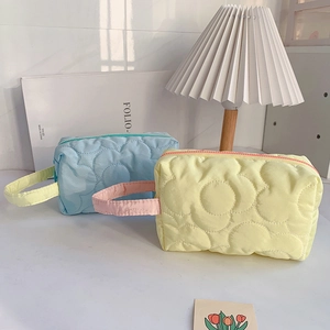 Quilted floral cosmetic bags in pastel blue and yellow with top handles and zippers