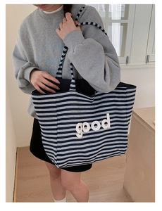 Close-up of navy and off-white striped tote bag with 3D good letter patch detail