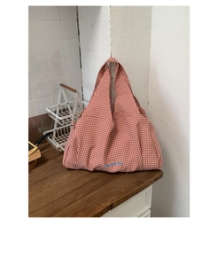 Detail of red checkered canvas tote with GoodThing embroidery on wood surface