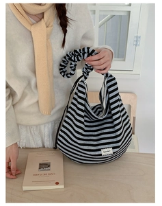 Close-up of striped canvas hobo bag with cloud-like gathered handle and lace tag detail