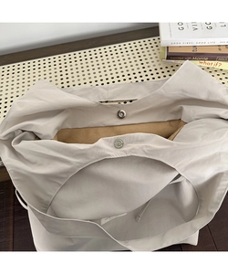 Close-up of beige nylon tote bag showing magnetic snap closure and tan suede lining