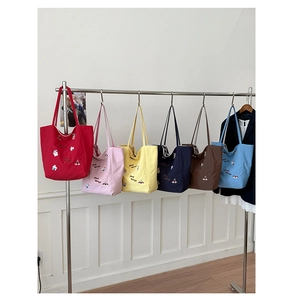 Détail de sacs cabas en toile colorés avec broderie cerise et texte good things brodé