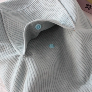 Detail of light blue ribbed fabric baby romper with snap buttons closure and soft texture