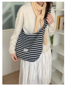 Detail of hobo shoulder bag with striped knit texture and adjustable strap on a model