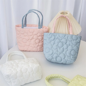 Detailed view of quilted floral handbags in various pastel colors on a white table