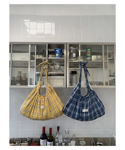 Detail of plaid pleated hobo bags in yellow and blue with tie shoulder straps