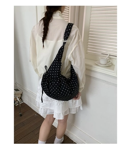 Detail of a black polka dot hobo bag with a wide drawstring pleated shoulder strap