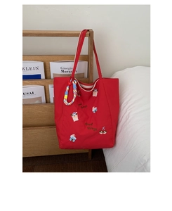 Détail du sac cabas en toile rouge avec broderie cartoon et breloque tissée