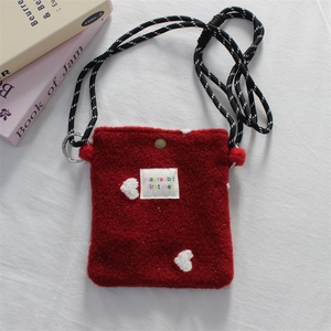 Detail of red plush mini crossbody bag with white heart pattern and braided strap