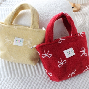 Détail de sacs à main en peluche jaune et rouge avec broderies nœuds blancs et fermeture