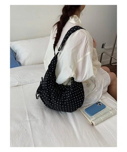 Close-up of black and white polka dot dumpling bag showing soft pleats and canvas texture