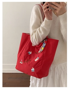 Détail du sac cabas en toile rouge avec broderie cartoon et texte good things sur l'épaule