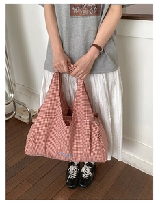 Detailed view of red gingham tote bag with blue embroidered letters and canvas texture