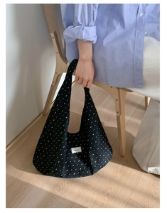 Detailed shot of black and white polka dot canvas tote bag with a woven brand tag